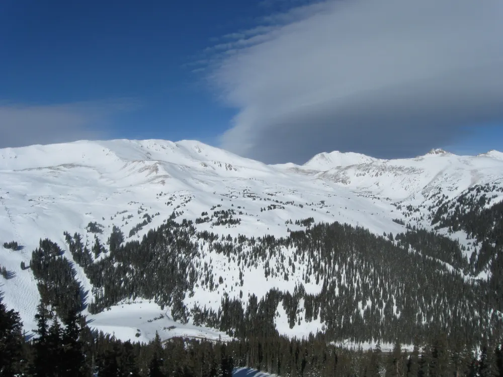 Loveland Ski Area under a lenticular cloud, with treed runs cut through the forest below the Continental Divide